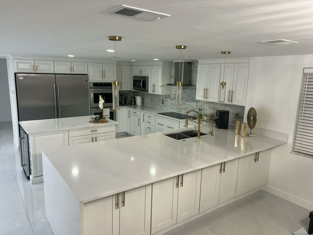 Finished white kitchen with quartz waterfall island, gold fixtures and custom cabinetry installed by Venet LLC