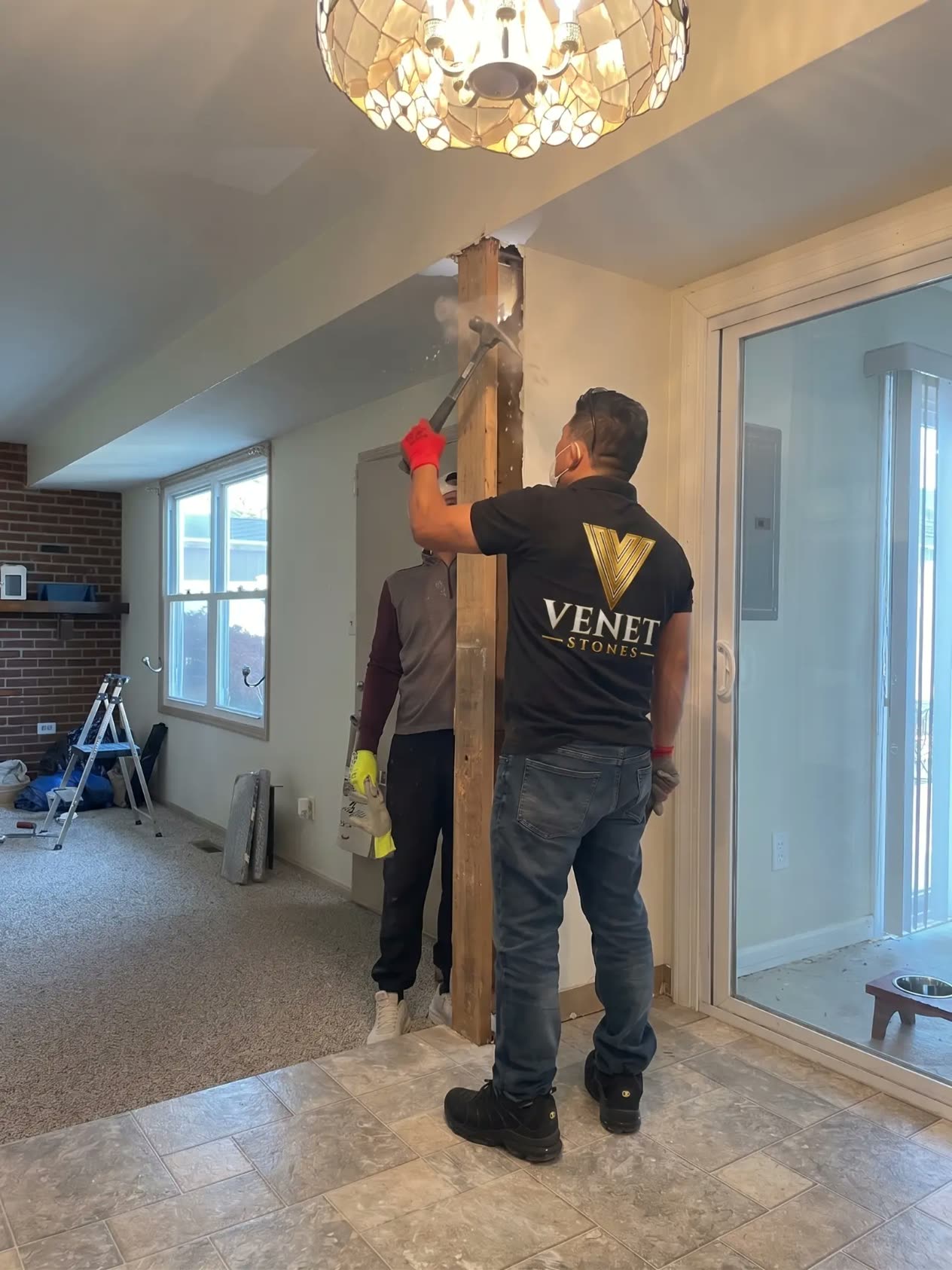 Venet Stones crew member in a branded black and gold shirt working alongside the owner on an interior remodeling job site